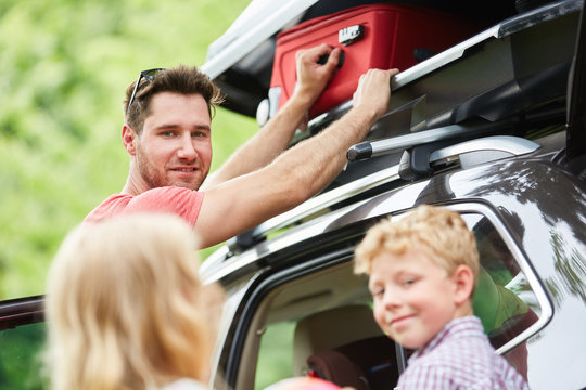 Familie verstaut Gep&auml;ck in der Auto Dachbox
