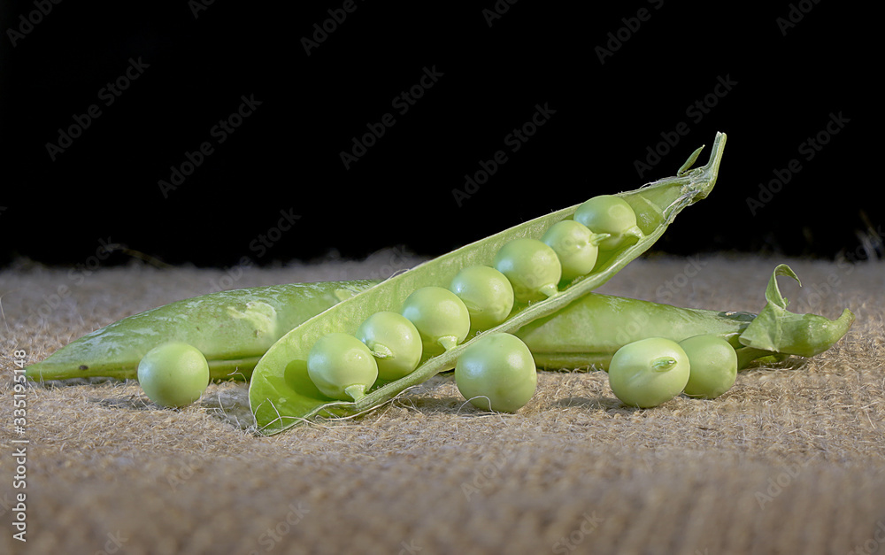 Wall mural hearthy fresh green peas and pods on rustic fabric background