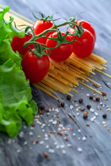 Dry spaghetti with sherry tomatoes and lettuce with spices, vertical photo