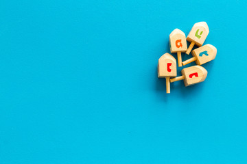 Dreidels - wooden symbol of Jewish holiday Hanukkah - on blue background top view copy space