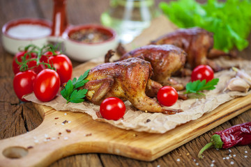 Dinner. Barbecue fried quail carcasses with on orange with tomatoes and fresh parsley and a glass of wine on a wooden table, top view