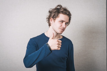 Man showing thumb up. Gray background.