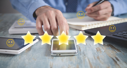 Man using smartphone with smileys and 5 star. Feedback