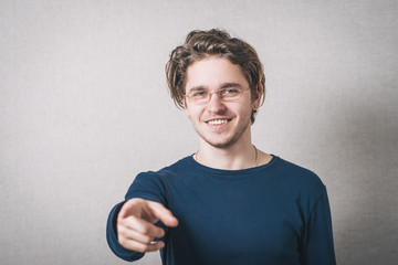 A man shows his index finger forward. Gray background.
