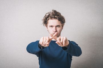 Man showing X fingers. Gray background.