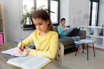 children, education and learning concept - mother with papers and laptop computer working at home office and daughter studying