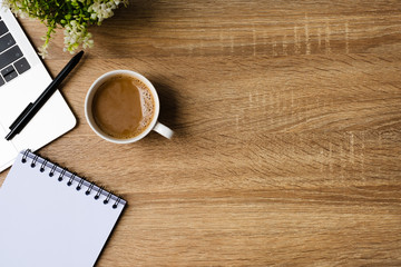 desk office with laptop, blank notepad, coffee cup and pen on wood table. Flat lay top view copy...