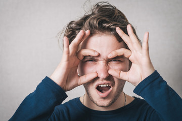 young man with hand over eyes, looking through fingers