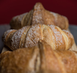 Colazione cornetti con un background rosso serviti su un piatto di legno