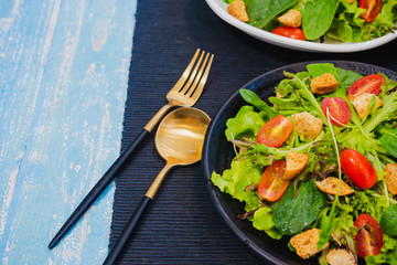 Couple bowl of healthy green vegetable salad on top with tomatos and biscuits. Side dish with salt pepper bottle, white cream and thousand island salad dressing