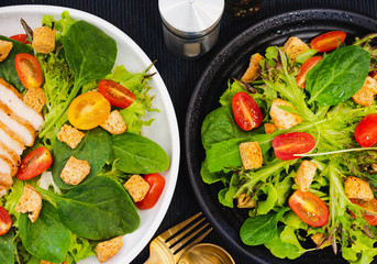 Couple bowl of healthy green vegetable salad on top with tomatos and biscuits. Side dish with salt pepper bottle, white cream and thousand island salad dressing