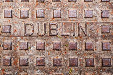 Dublin sign on a metal manhole, rusty weathered surface, selective focus.