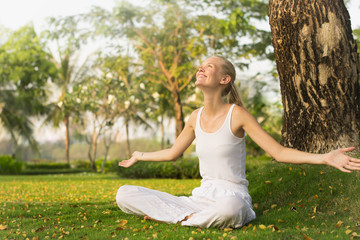 A happy woman embracing the sunshine in nature. Relaxation outdoor.