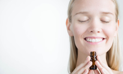 A pretty woman holding a bottle of essential oils, breathing the aroma. Natural alternative...