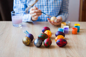Fototapeta na wymiar Holidays, handmade and creation concept - Girl draws on Easter egg, close-up.