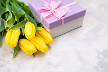 Bouquet of yellow tulips and gift box top view. Happy spring holidays. Birthday, Easter, Mother's day, Valentines, Women's day, Wedding concept. Holidays card, presents, invitation, banner. Copy space
