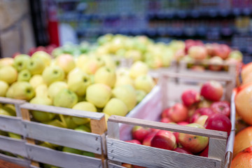 Soft focused shot of fruit department in grocery store, supermarket, mall, hypermarket or shopping center. Red, yellow and green apples in boxes. Healthy eating, avitaminosis  concept.