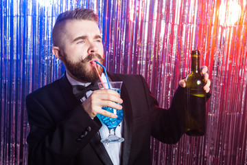 Club party and holidays concept - Portrait of elegant handsome man in a expensive suit holds blue cocktail on shiny background.
