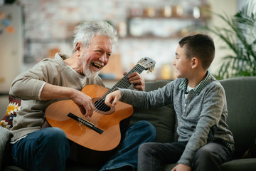 Grandpa and grandson playing guitar. Grandfather and grandson enjoying at home.	