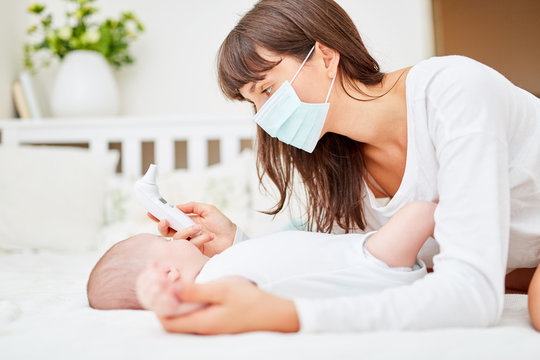Mutter und Baby beim Fieber messen mit Thermometer