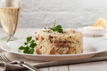 Wild mushroom risotto with parsley and parmesan on a white wooden background