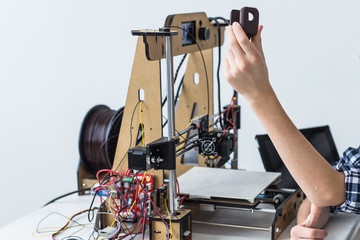 Education, children, technology concept - teen boy is printing on 3d printer.