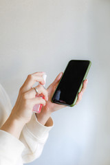 girl wipes the phone with an antiseptic from dirt and viruses, disinfection