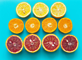 Fototapeta na wymiar Top view on multi-colored halves of juicy fresh citruses on a bright turquoise plastic cutting board. Appetizing fruit background. Vitamin C-rich fruits are good for coronavirus infection.