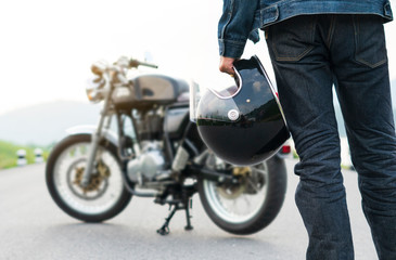 Fototapeta na wymiar Biker riding in jean is holding a helmet and motorcycle blur background.