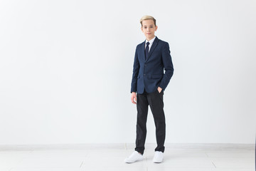Portrait of stylish school boy teenager in white shirt and jacket against white background. © satura_