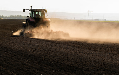 Naklejka premium Tractor is preparing the land at dusk