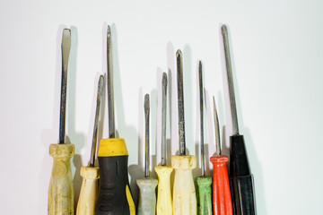 A lot of screwdrivers of different colors on a white background. Necessary tools.