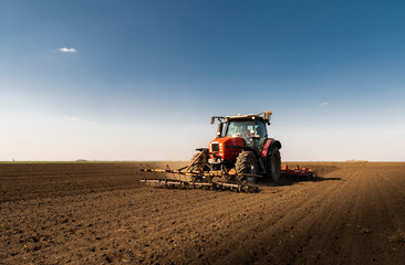 Naklejka premium Tractor is preparing the land at dusk