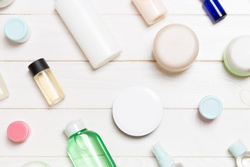 Top view of different cosmetic bottles and container for cosmetics on white wooden background. Flat lay composition with copy space