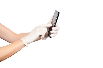 Young woman holding a mobile phone in her hands wearing disposable latex protective gloves isolated on white.