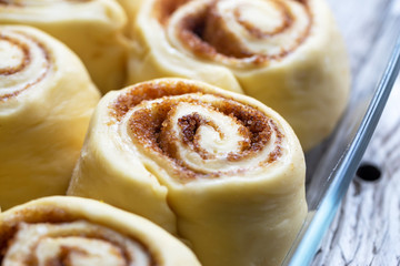 Raw homemade cinnamon buns on wooden table, bevor baking, dark background, copy space, top view.