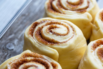 Raw homemade cinnamon buns on wooden table, bevor baking, dark background, copy space, top view.