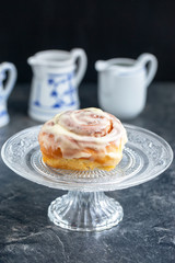 Glazed homemade cinnamon buns on a dark table, dark background, copy space, top view.