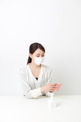 マスクをしながら手を消毒する女性