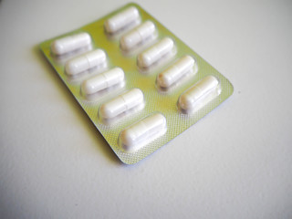 Medication in the form of a package of white oval capsules on a gray background