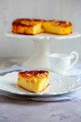 Homemade cheesecake with sliced almonds on plate on grey table. Selective focus, natural light.