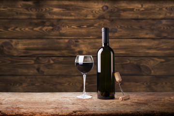 Pouring red wine into the glass against wooden background