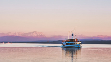 Sunset on a lake with a boat and view of mountains, view of Alps