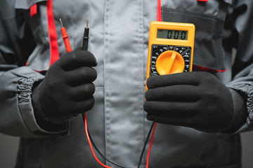 Electrician holding in hands a multimeter close up.