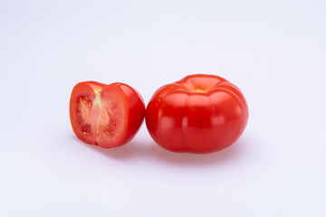 Red tomatoes sliced in half in front of a white background