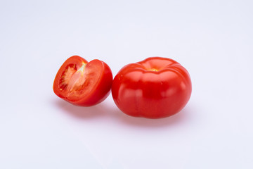 Red tomatoes sliced in half in front of a white background
