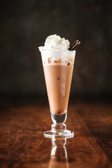 delicious cold chocolate ice cream milkshake with cookie in a long glass, dark wooden background, side view, vertical