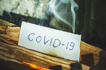 COVID-19 virus destroying humanity worldwide written on a piece of paper burns with fire