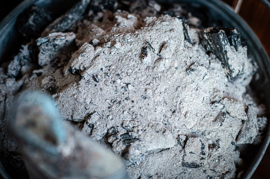 Charcoal and ash are cleaned from the home fireplace in an iron galvanized bucket.