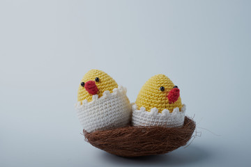 crochet Easter egg cup in chicken shape with easter eggs and greeen wool grass. white isolated background